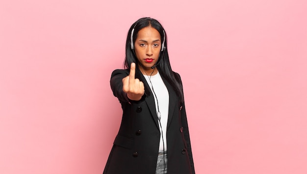 Jonge zwarte vrouw voelt zich boos, geïrriteerd, opstandig en agressief, draait de middelvinger om en vecht terug. telemarketing concept