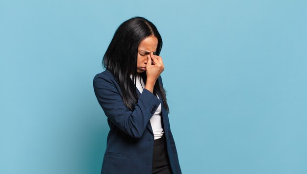 jonge zwarte vrouw voelt zich gestrest, ongelukkig en gefrustreerd, raakt het voorhoofd aan en lijdt aan migraine of ernstige hoofdpijn. bedrijfsconcept
