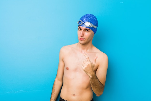 Foto jonge zwemmersmens die met vinger op u richten alsof uitnodigend dichterbij kom.