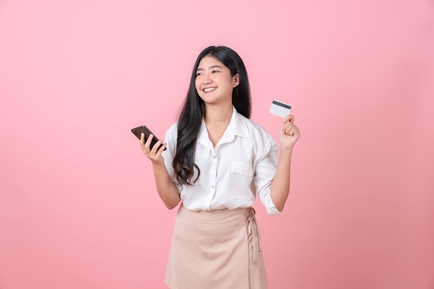 Jongelui die de Aziatische creditcard van de vrouwenholding met smartphone glimlachen en ruimte kijken te kopiëren