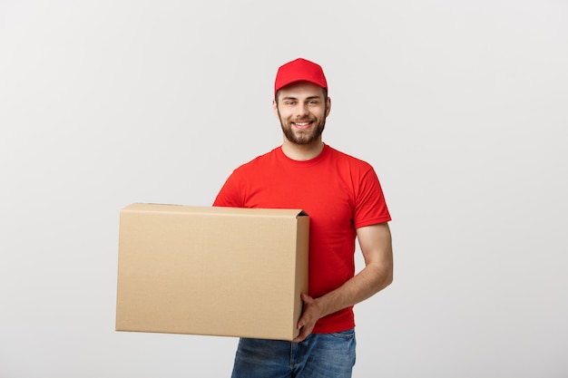 Jongelui die logistische leveringsmens in rode eenvormig houden die de doos op wit houden