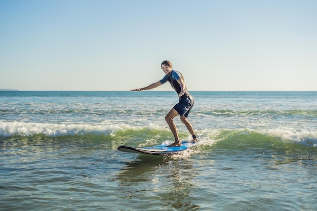 Jongeman, beginner Surfer leert surfen op een zeeschuim op het eiland Bali