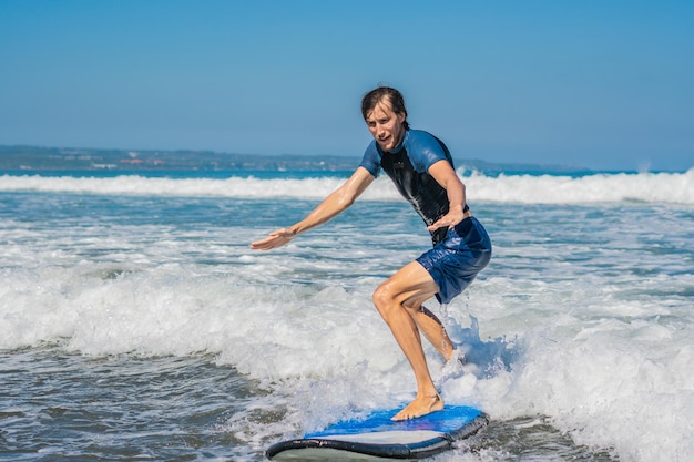 Jongeman, beginner Surfer leert surfen op een zeeschuim op het eiland Bali