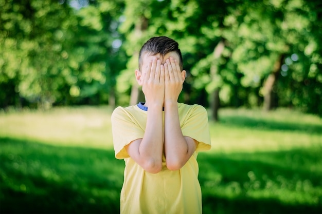 Jongen bedekt gezicht met zijn handen