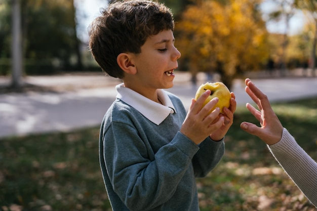 Jongen die appel eet dichtbij moeder