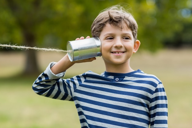 Jongen die door de telefoon van het tinblik luistert