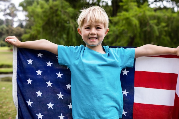 Jongen die een Amerikaanse vlag in het park houdt