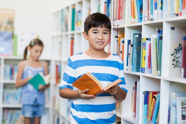 Jongen die een boek in bibliotheek houdt