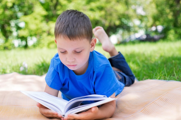 Foto jongen die een boek leest terwijl hij in het park ligt