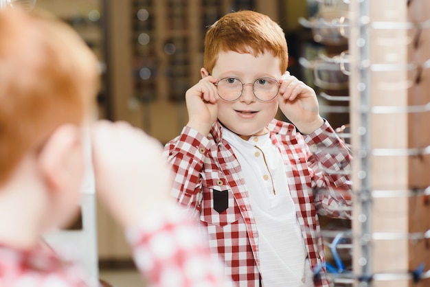 Jongen die een bril kiest bij optica-winkel.