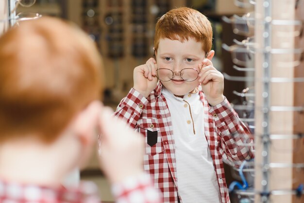 Jongen die een bril kiest bij optica-winkel.