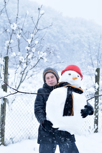 Jongen die een sneeuwman, leuke de winteractiviteiten maakt