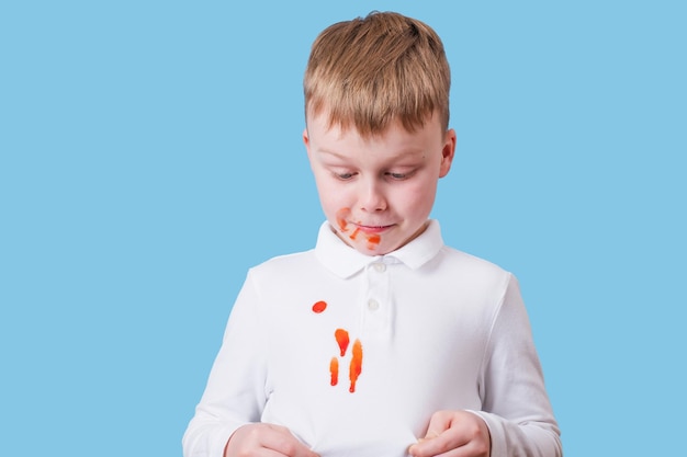 Jongen die een vlek laat zien van tomatensaus en spaghetti op zijn t-shirt
