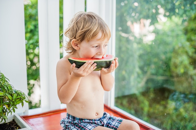 Jongen die en watermeloen glimlacht eet