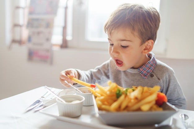 Jongen die eten op tafel eet