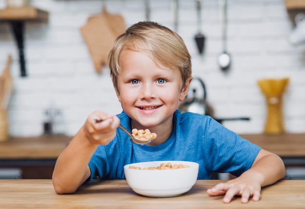 Jongen die graangewassen eet terwijl het bekijken de camera