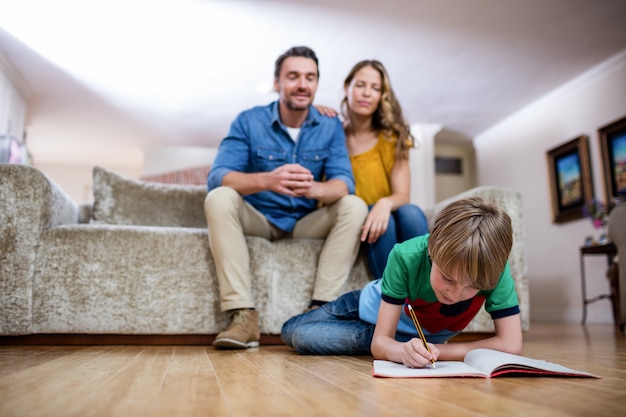 Jongen die huiswerk doet terwijl ouders die op bank zitten