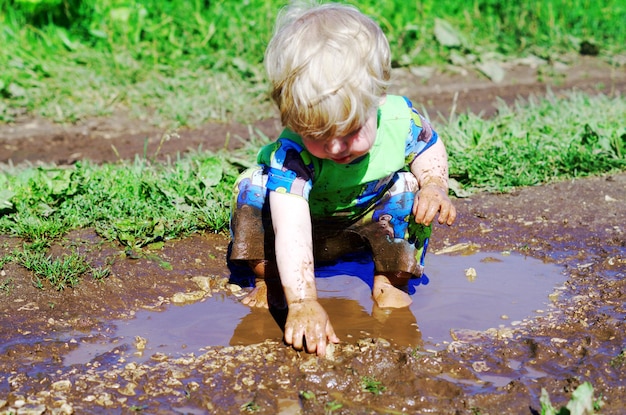 Jongen die in een modderige plas speelt