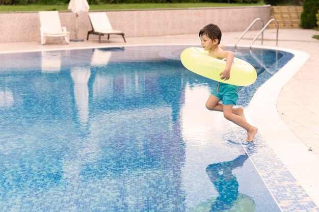 Foto jongen die in pool met vlotter springt