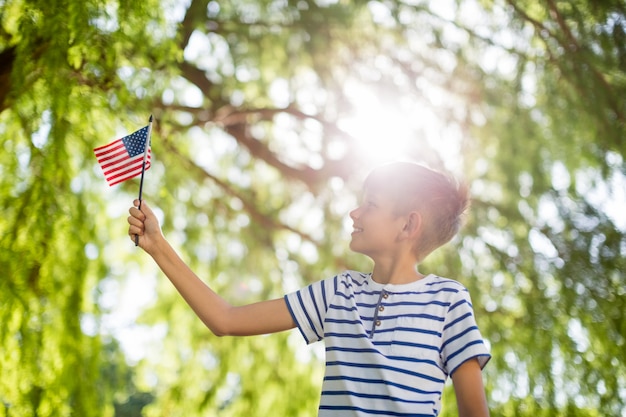 Jongen die kleine Amerikaanse vlag in park houdt