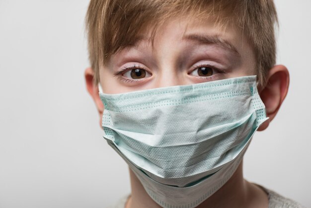 Jongen die medisch masker draagt om tegen virussen te beschermen. Portret kind close-up in chirurgisch masker.