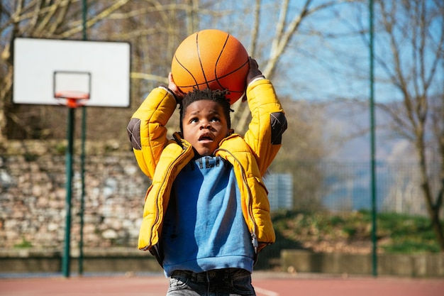 Jongen die met basketbal speelt op het veld