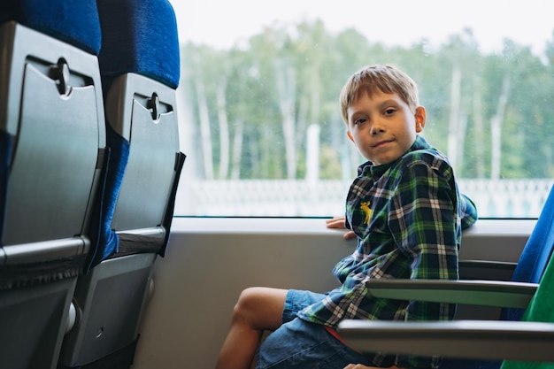 Jongen die met de trein reist, zit bij het raam en kijkt naar buiten