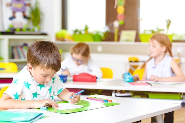 Jongen die op papier tekent aan een bureau in de klas