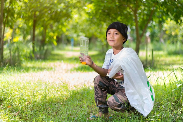 Jongen die plastic flessen verzamelt in het park Copyspace