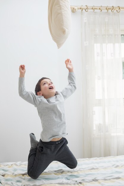 Jongen die plezier heeft in de slaapkamer op het bed