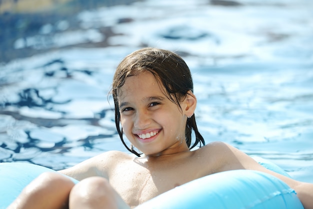 Jongen die pret het spelen met water op de zomerpool heeft