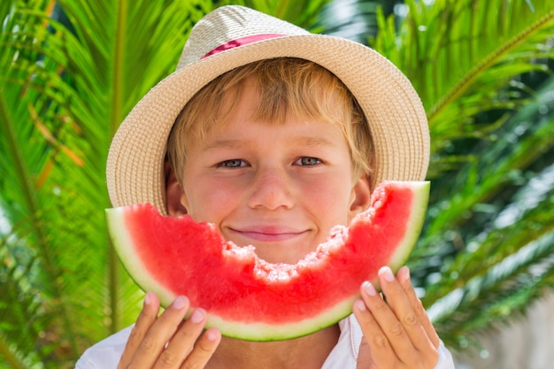 Jongen die rode rijpe watermeloen eet Zomervakantie en vakantieconcept