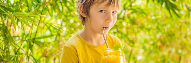 Jongen die sappige smoothie drinkt van mango in glazen glazen pot gezond leven concept kopie ruimte banner