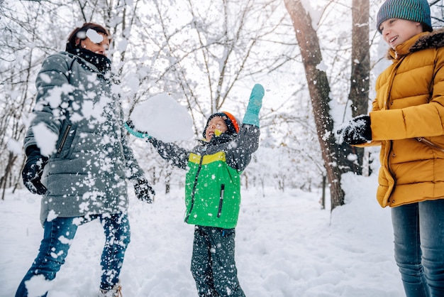 Jongen die sneeuw in de lucht met familie werpt