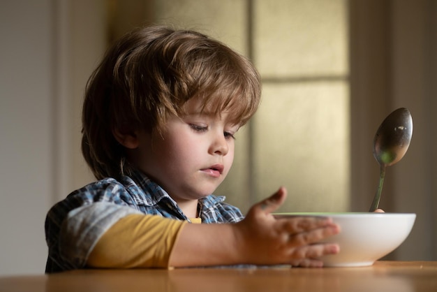 Jongen die thuis gezond voedsel eet Goedemorgen in het gelukkige gezin Kleine jongen die aan tafel zit en een melksnack eet