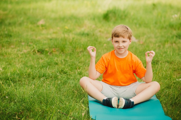 Jongen die Yoga in openlucht op Groen Gras doet.