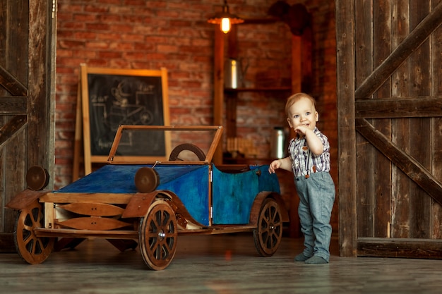 Jongen die zich bij de werktuigkundige met hulpmiddelen retro auto dichtbij de garage bevindt