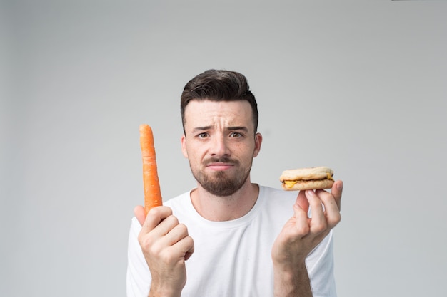 Jongen eet een wortel en hamburger