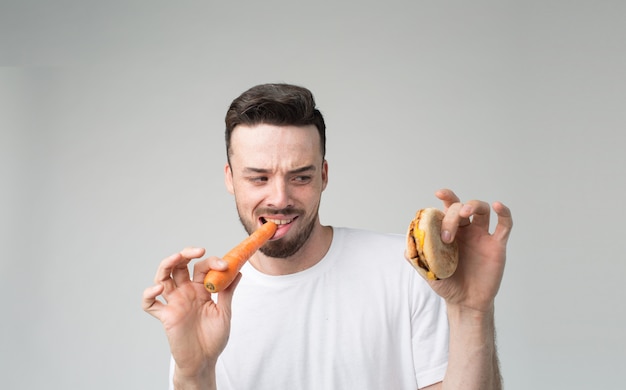 Jongen eet een wortel en hamburger