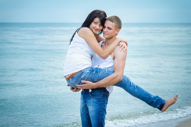 Jongen en een meisje in jeans en witte t-shirts aan de kust