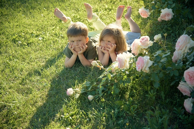 Jongen en meisje bij bloeiende roze bloemen op gazon