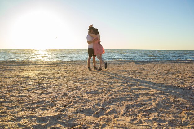 Jongen en meisje dansen op het strand bij zonsopgang