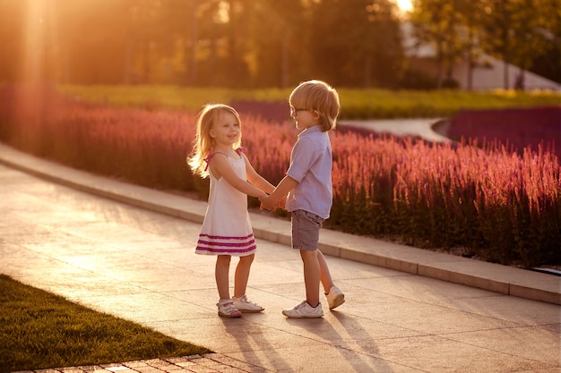 Jongen en meisje die elkaars handen houden bij zonsondergang