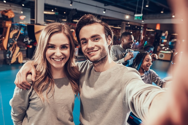 Jongen en meisje in arcade. Het paar neemt selfie.