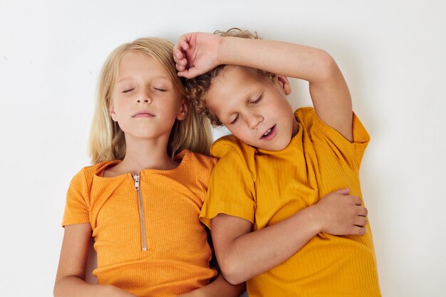Jongen en meisje liggen op een witte achtergrond in gele t-shirts emoties