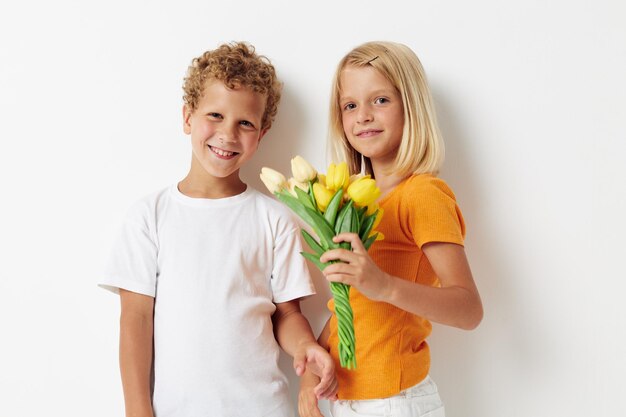 Jongen en meisje met een boeket bloemen cadeau verjaardag vakantie jeugd lichte achtergrond