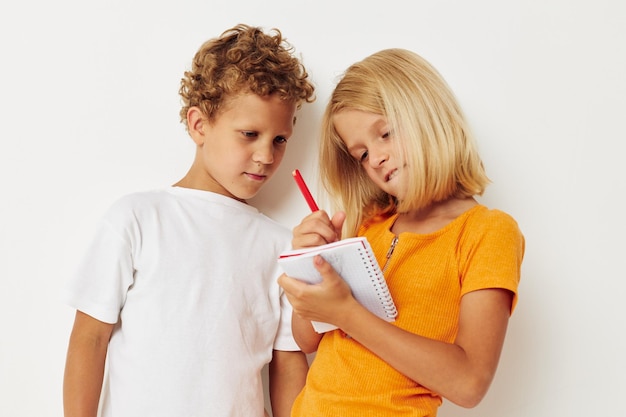 Jongen en meisje plezier in kleurrijke t-shirts met een notitieblok geïsoleerde achtergrond ongewijzigd