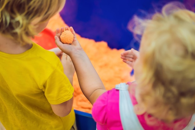 Foto jongen en meisje spelen met kinetisch zand