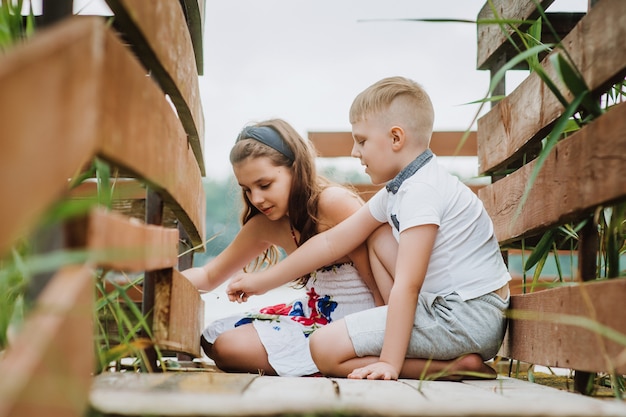 Jongen en meisje stitting op een houten pier, zomervakantie