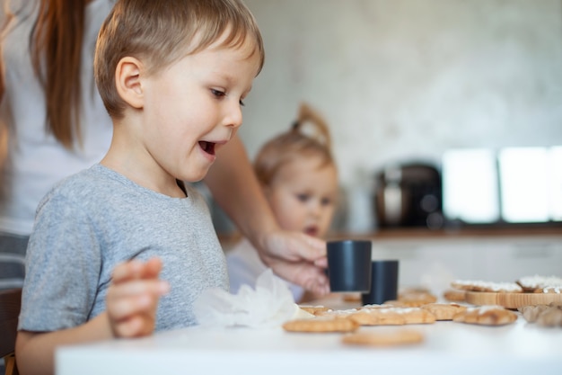 Foto jongen en meisje versieren kerst peperkoek thuis een jongen en een meisje schilderen met kornetten met suiker i...